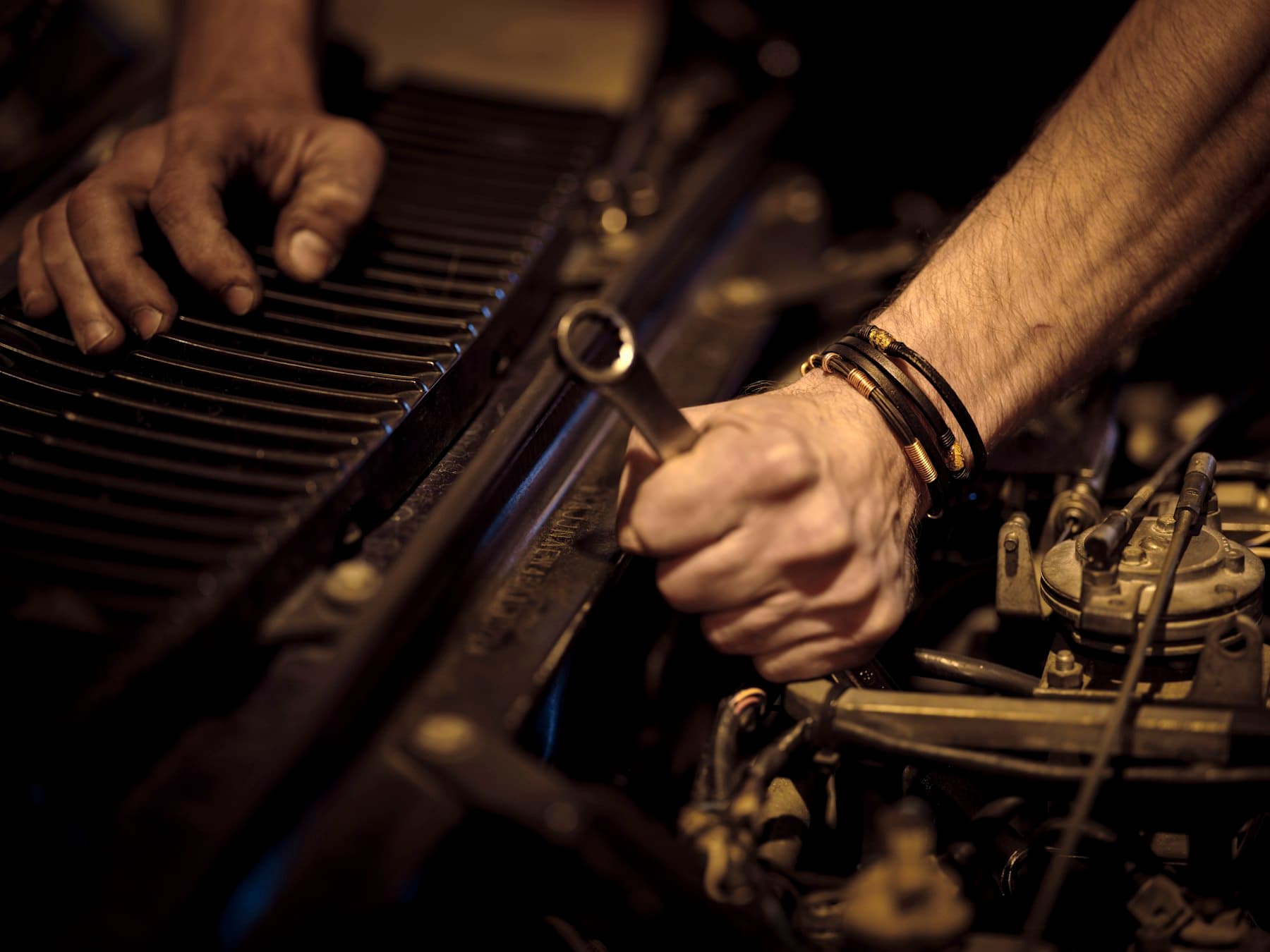 Hands working in an engine bay. Demonstration photograph. Not verified work from this shop.