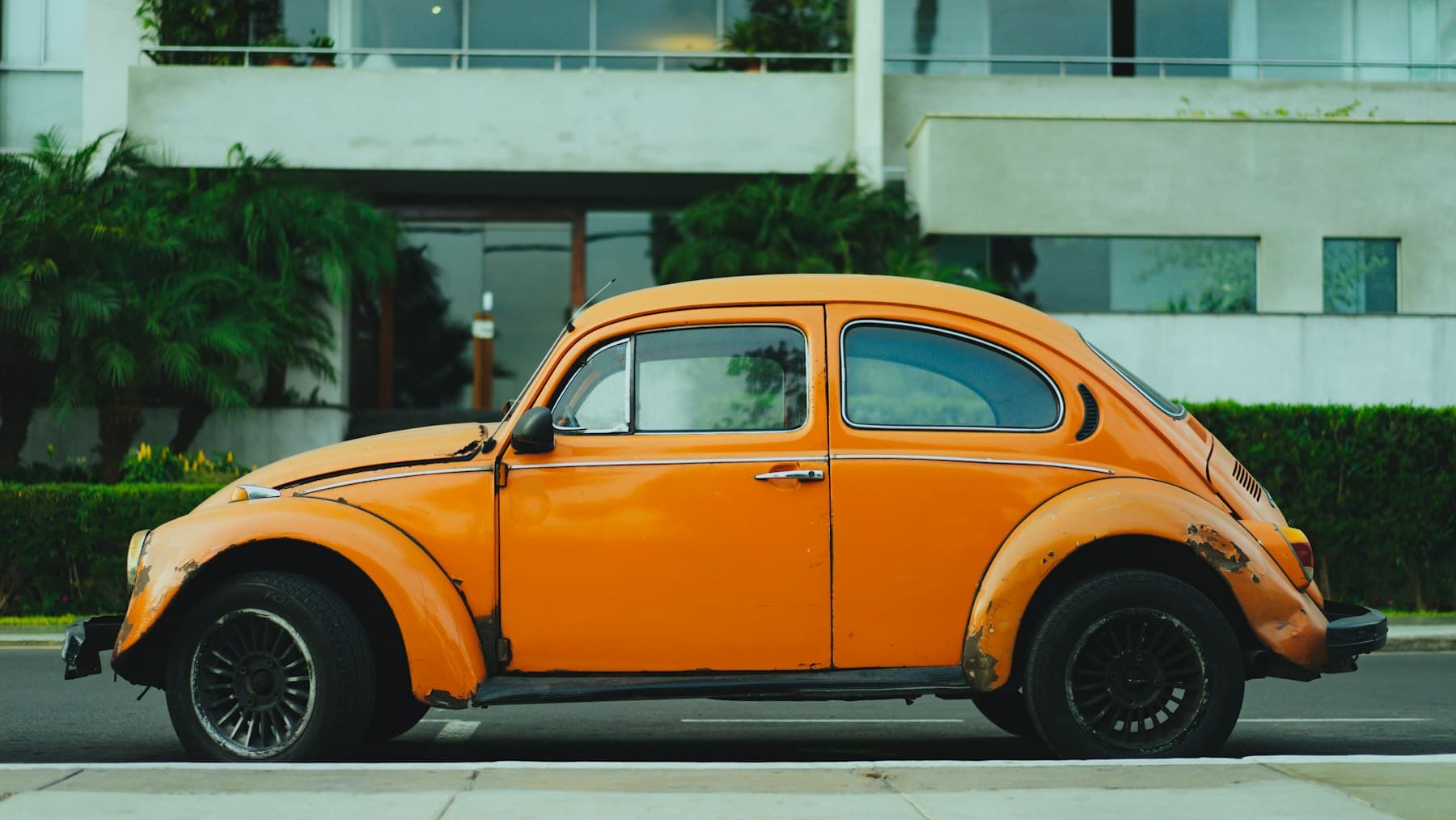 Orange classic coupe parked on a street. Demonstration photograph. Not verified work from this shop.